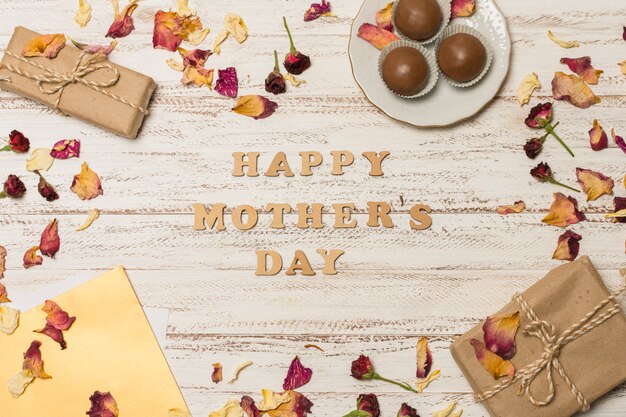 Happy mothers day title between paper near plate with candies and present boxes