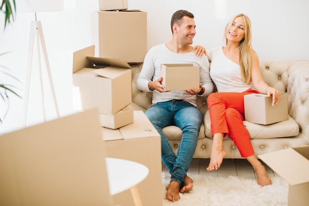 Happy moved in couple sitting with boxes