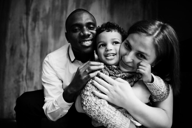 男の子の子供と幸せな多民族の家族はレストランで時間を過ごすアフリカの男性と白人のヨーロッパの女性の関係