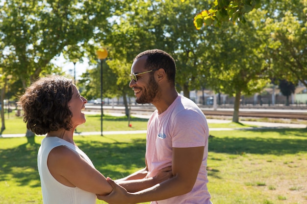 Free photo happy multiethnic friends holding hands in park