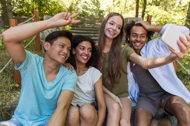 Happy multiethnic friends students outdoors make selfie