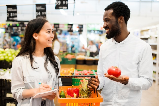 Happy multiethnical couple choosing goods in supermarket