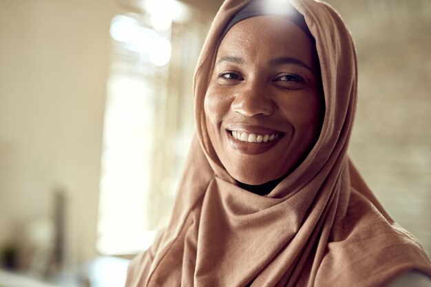 Счастливая мусульманская деловая женщина смотрит в камеру во время работы в офисе