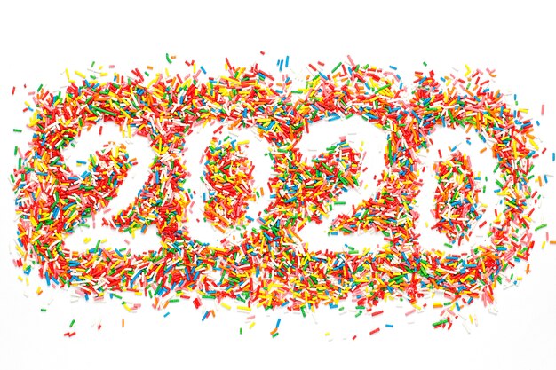 2020 년 새해 복 많이 받으세요. 밝은 무지개 설탕 뿌리와 다채로운 숫자 모양에 격리 된 화이트