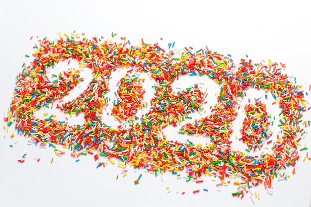  Happy New 2020 Year. Colorful number shape with bright rainbow sugar sprinkles isolated on white