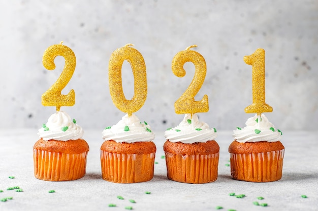 Free photo happy new year 2021, cupcakes with golden candles.