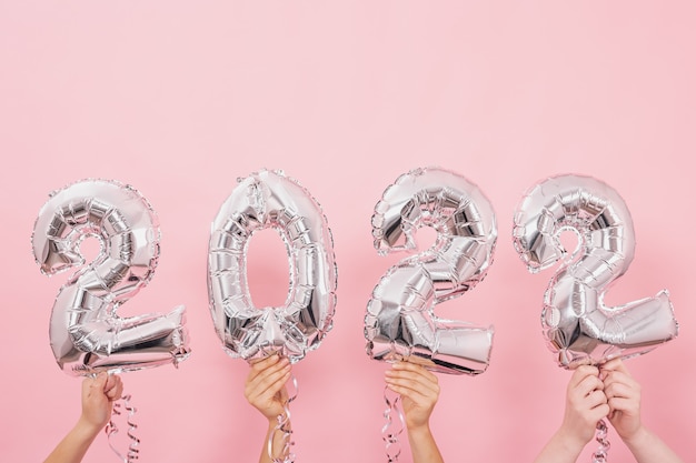 Happy new year 2022 celebration. silver foil balloons numeral 2022 on a pink background.