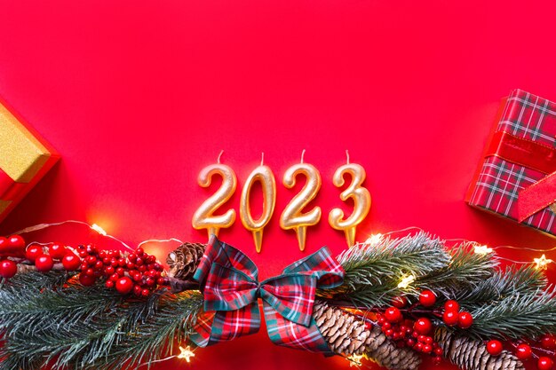 Premium Photo | Happy New Year- Golden Candles Numbers 2023 On A Red Background With Christmas Tree, Sequins, Stars, Glitter, Gift Boxes. Greetings, Postcard. Calendar, Cover.