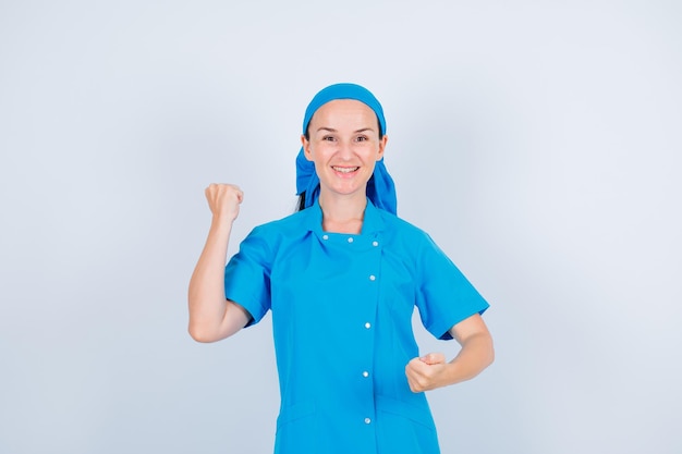 Happy nurse is looking at camera by raising up her fist on white background