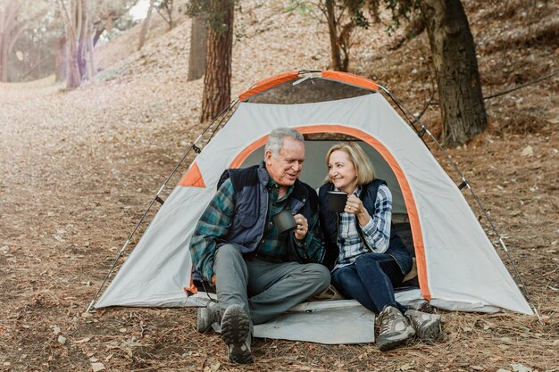 숲에서 텐트에서 커피를 마시고 행복 한 오래 된 커플