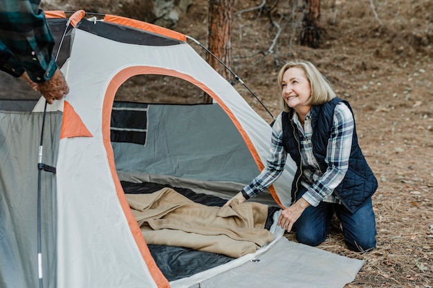 Happy old couple setting up a tent in the forest