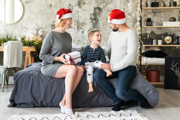 Genitori felici e bambino che stanno insieme il giorno di natale