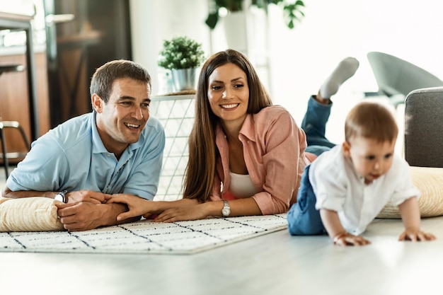 Счастливые родители наслаждаются, наблюдая, как их малыш ползает по полу в гостиной
