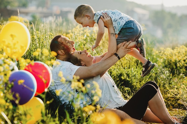 Happy parents have fun with their child on green lawn under the tree