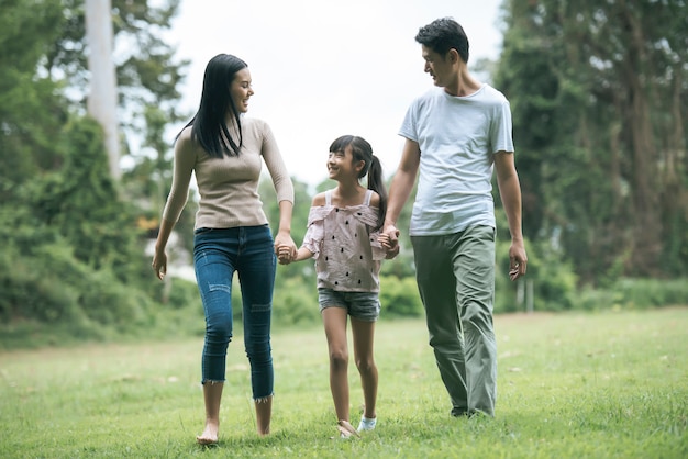 Happy parents and their daughter walking in the park, Happy family concept.