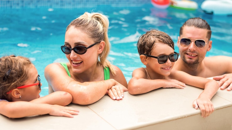 Free Photo happy parents and two kids are holding on to the side of the pool