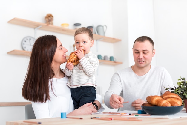 Счастливые родители с ребенком на кухонном столе