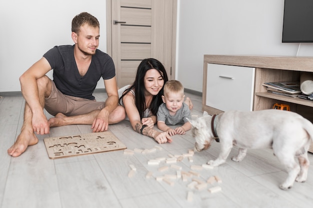 Happy parents with her little son looking at dog smelling wooden blocks