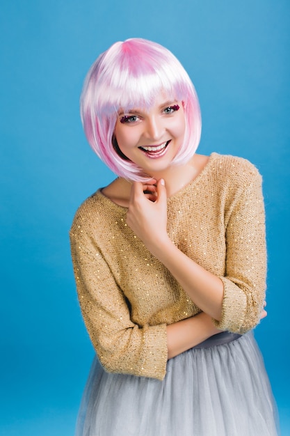 Happy party time of young attractive woman in grey tulle skirt . Golden sweater, cut pink hair, brightful makeup, expressing positivity, smiling, celebrating new year, birthday.