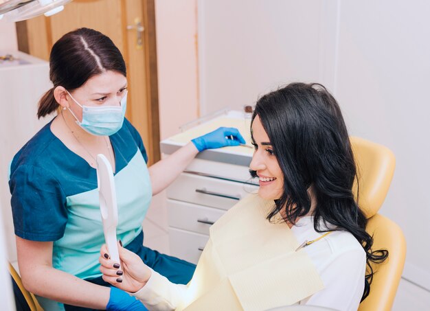 Happy patient looking at mirror in dental office 