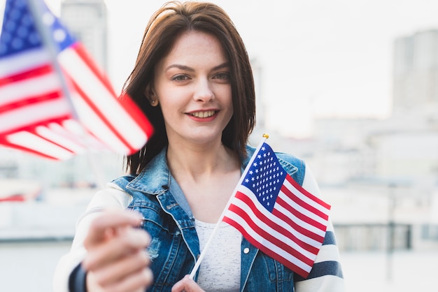 Felice donna patriottica che mostra bandiere americane