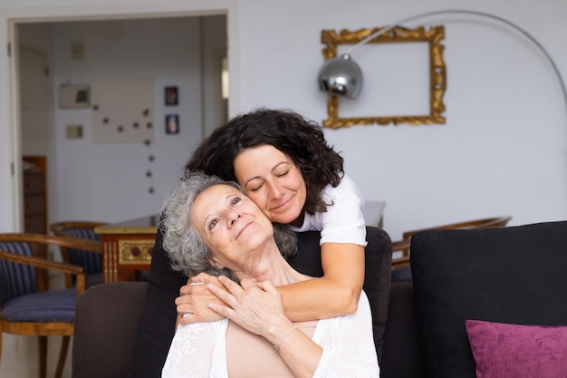 Happy peaceful middle aged woman hugging elderly lady
