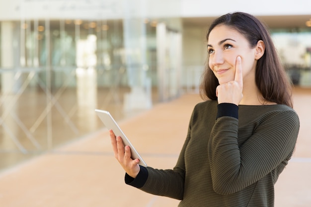 Happy pensive tablet user looking at copy space away