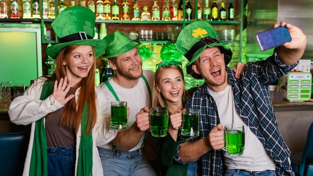 Foto gratuita persone felici che celebrano st. patrick's day e prendendo selfie