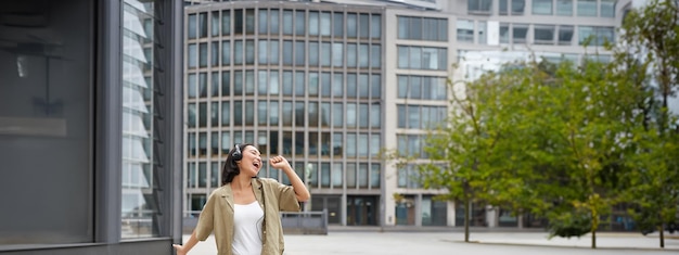 Free photo happy people in city upbeat young girl dancing on street in headphones listening music in headphones