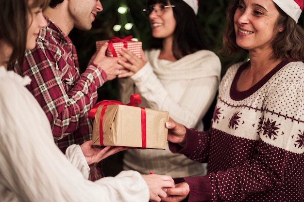 Free photo happy people exchanging gifts at christmas celebration