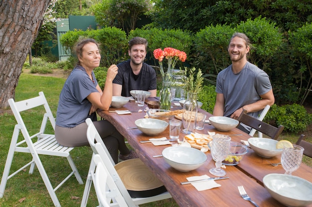 無料写真 裏庭の木製のテーブルで朝食を食べて幸せな人々