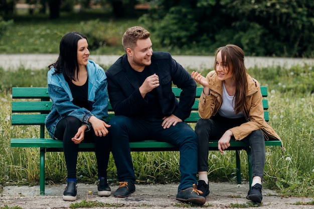 Free photo happy people relaxing on bench and talking