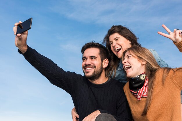 Happy people taking selfie on blue sky background