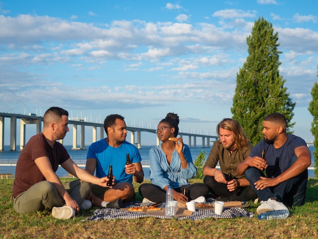 Happy people talking and drinking beer during summer picnic. Good friends talking and drinking beer. Concept of picnic