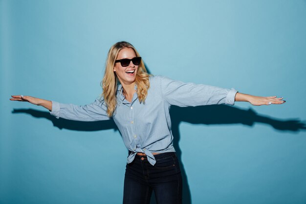 Happy playful blonde woman in shirt and sunglasses looking away