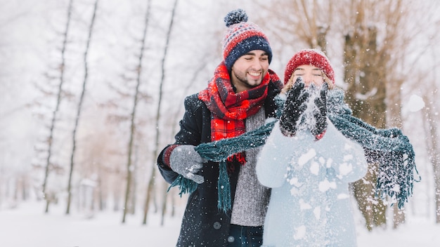 幸せな遊びのカップルは、雪を投げる