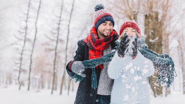 Happy playful couple throwing snow