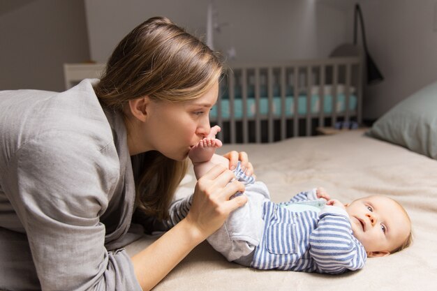 Happy playful new mom holding baby legs