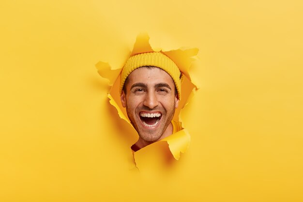 Happy pleased man with toothy smile, wears hat