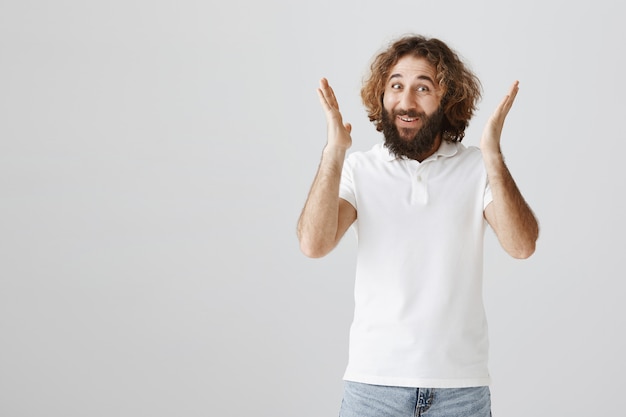 Happy pleased middle-eastern guy raising hands up upbeat