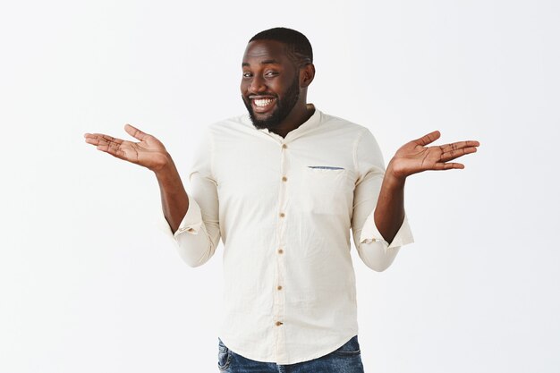 Happy and pleased young guy posing against the white wall