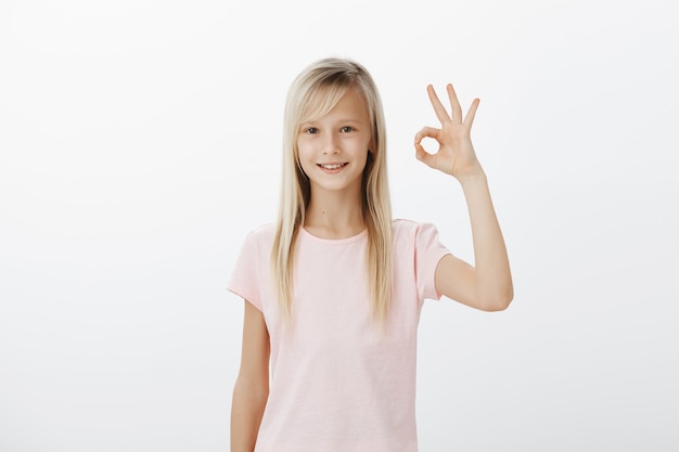 Счастливый довольный молодой ребенок показывает нормальный жест, одобряет или рекомендует