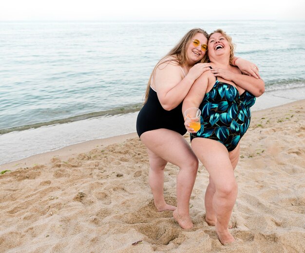 Happy plus size friends standing in the sand