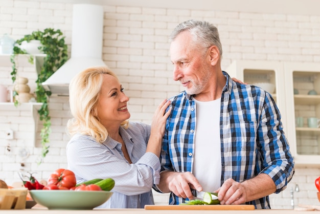 台所で食べ物を準備する年配のカップルの幸せな肖像画