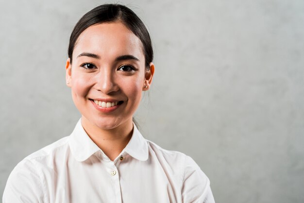 Happy portrait of a young asian businesswoman standing against grey background