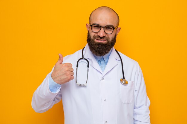 Happy and positive bearded man doctor in white coat with stethoscope around neck wearing glasses looking smiling showing thumb up