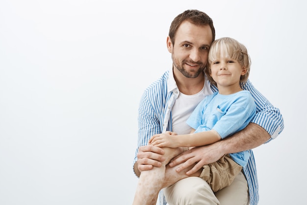 happy positive father and son with vitiligo, hugging and smiling broadly, being pleased and satisfied spending time together