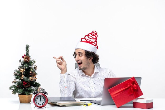 Happy positive surprised young businessman with funny santa claus hat speaking to someone in the office on white background