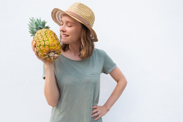 Счастливая положительная женщина в шляпе лета пахнуть целым ананасом