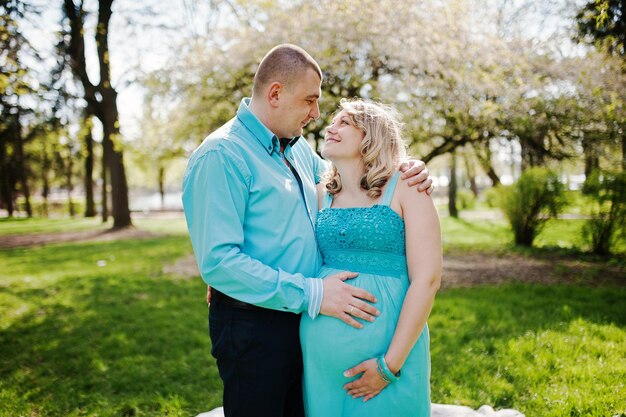 Happy pregnant couple hugging in nature background spring blossom tree